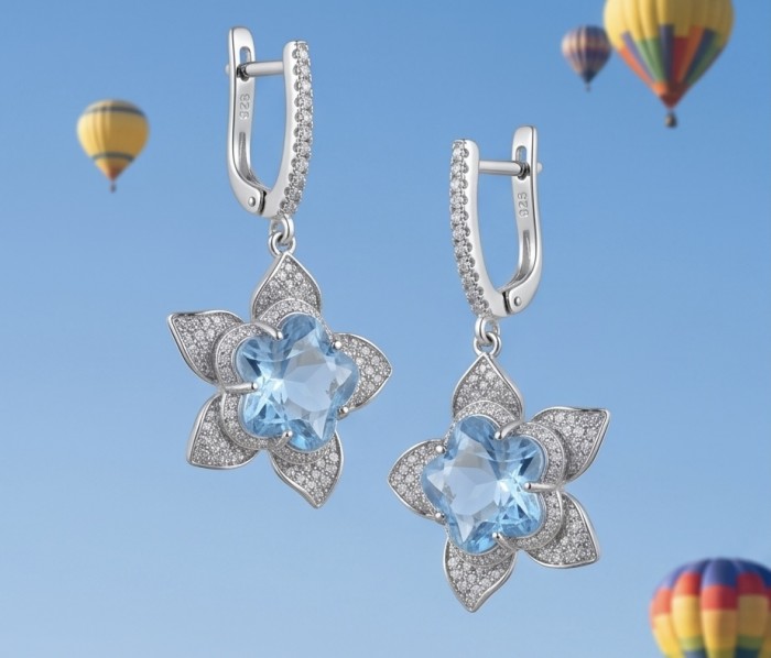 Forget -Me- Not flower 10.5 carat genuine Swiss Blue Topaz .925 Sterling Silver handmade Statement earrings - Close-up of flower-shaped Swiss Blue Topaz earrings, hot air balloons behind.