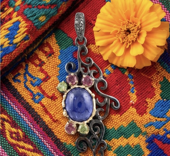 Summer Fiesta 9.5 carat natural Tanzanite black rhodium over .925 Sterling Silver Handcrafted Pendant - Tanzanite pendant close-up with colorful textile and marigold flower.