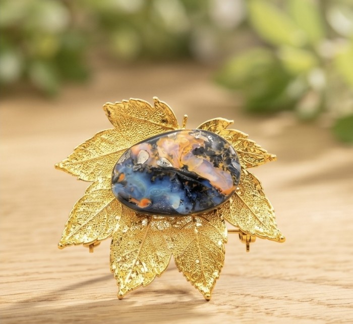 Stylish REAL Leaf dipped in 14K Gold 24.5 CARAT Boulder Opal .925 Sterling Silver Pendant - Gold leaf with opal brooch, angled front view on wooden surface.