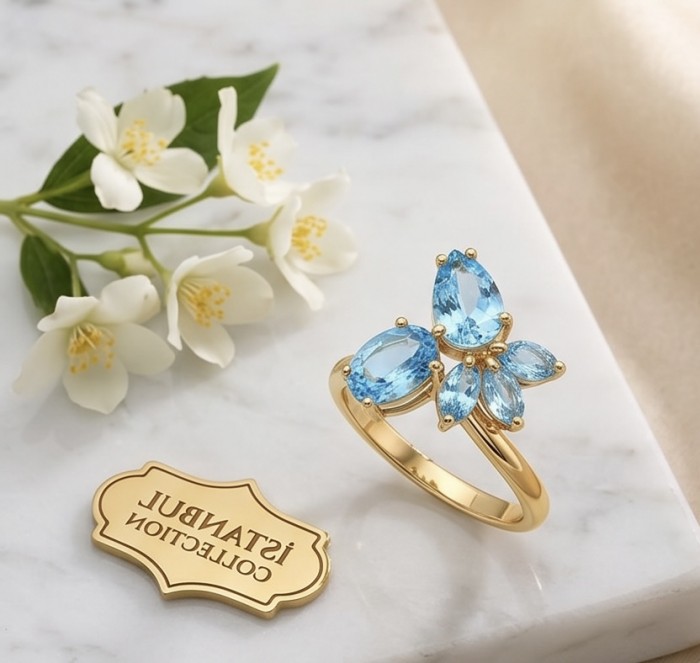 Pacifica 6.8 carat Swiss Blue Topaz 22K Gold over .925 Sterling Silver handcrafted ring size 8 - Pacifica Swiss Blue Topaz ring on marble with jasmine flowers, top view