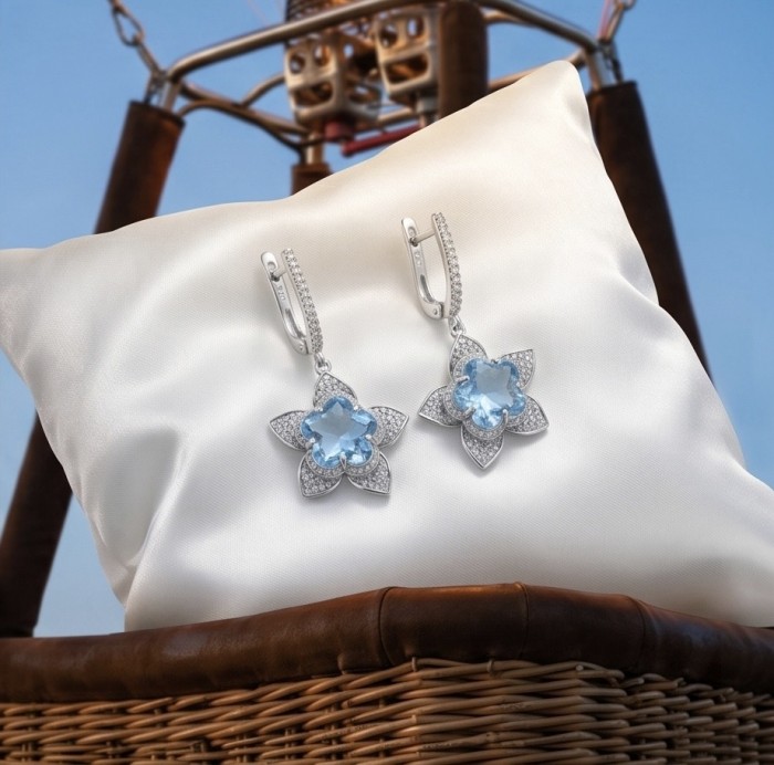 Forget -Me- Not flower 10.5 carat genuine Swiss Blue Topaz .925 Sterling Silver handmade Statement earrings - Close-up of Swiss Blue Topaz flower earrings on white cushion in a basket.