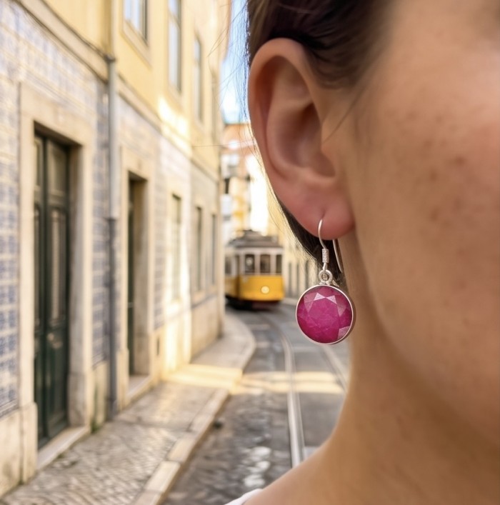 Born to Glam uthentic 15.2 carat Ruby .925 Sterling Silver handcrafted earrings - Ruby earring close-up, worn on ear, tram in background.