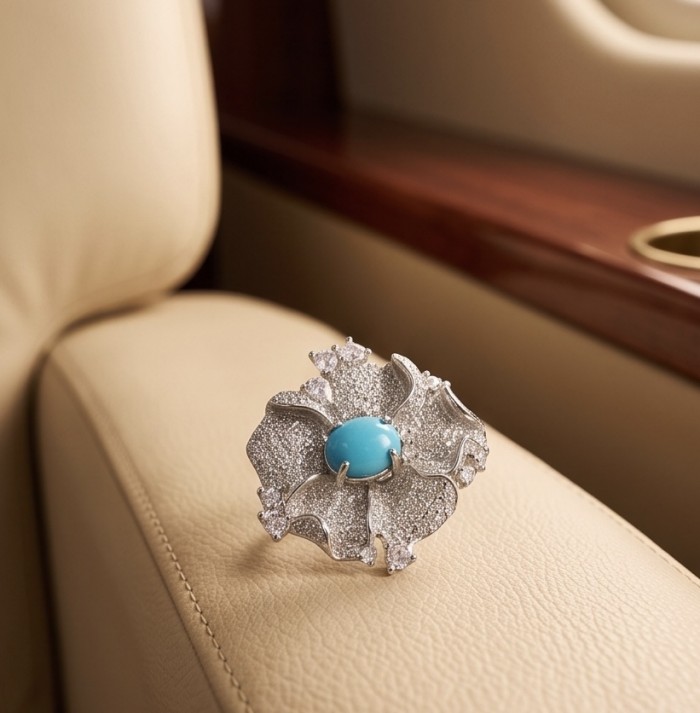 Pacifica - 3.4 carat Sleeping Beauty Turquoise .925 Sterling Silver handmade Statement Ring size 8 - Floral diamond ring with turquoise stone, angled on leather seat.