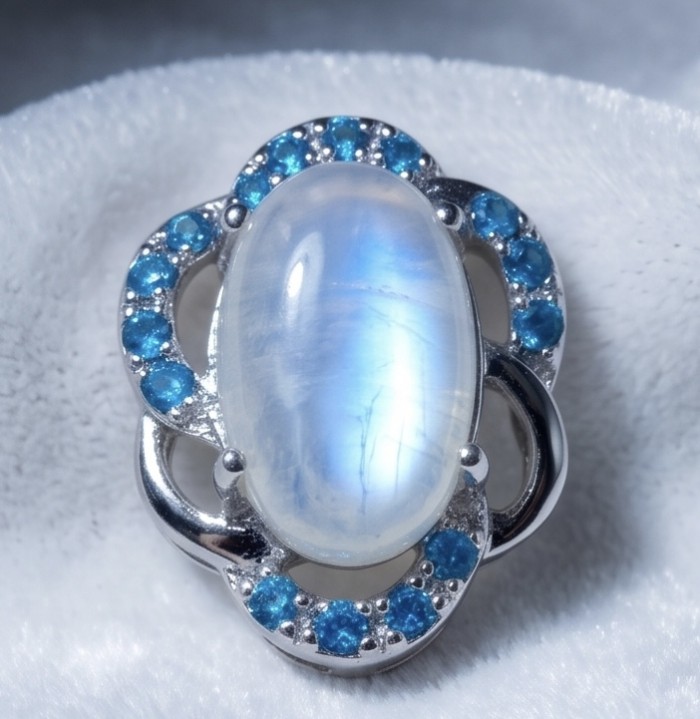 Genuine 7.2 carat Fire Moonstone .925 Sterling Silver handcrafted pendant - Close-up of Fire Moonstone ring with blue accents on white background