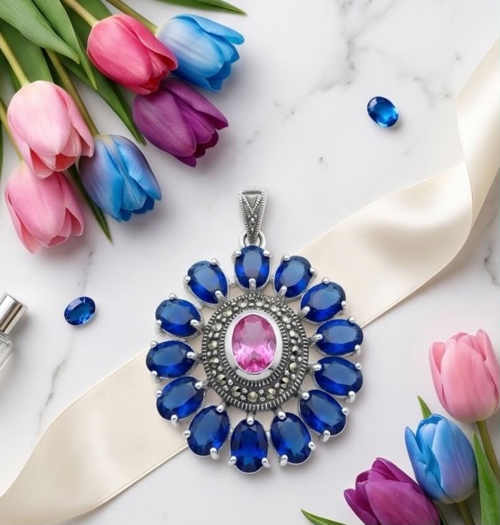 Marvelous Natural 20.8 carat Pink Topaz London Blue Topaz .925 Sterling Silver Handcrafted pendant - Pendant with pink and blue topaz stones on a marble surface with tulips.