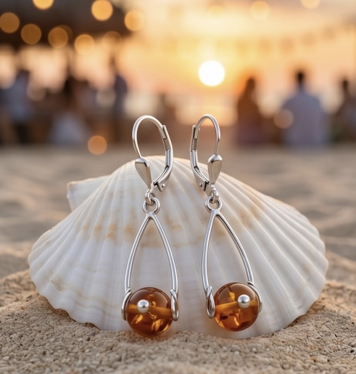 Wonderful Baltic Amber .925 Sterling Silver entirely handcrafted earrings - Amber silver earrings against a seashell at sunset, side view.