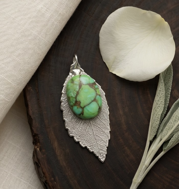 Stylish REAL Leaf dipped in .925 Sterling Silver Turquoise Pendant - Turquoise on silver leaf pendant, top view on textured surface.