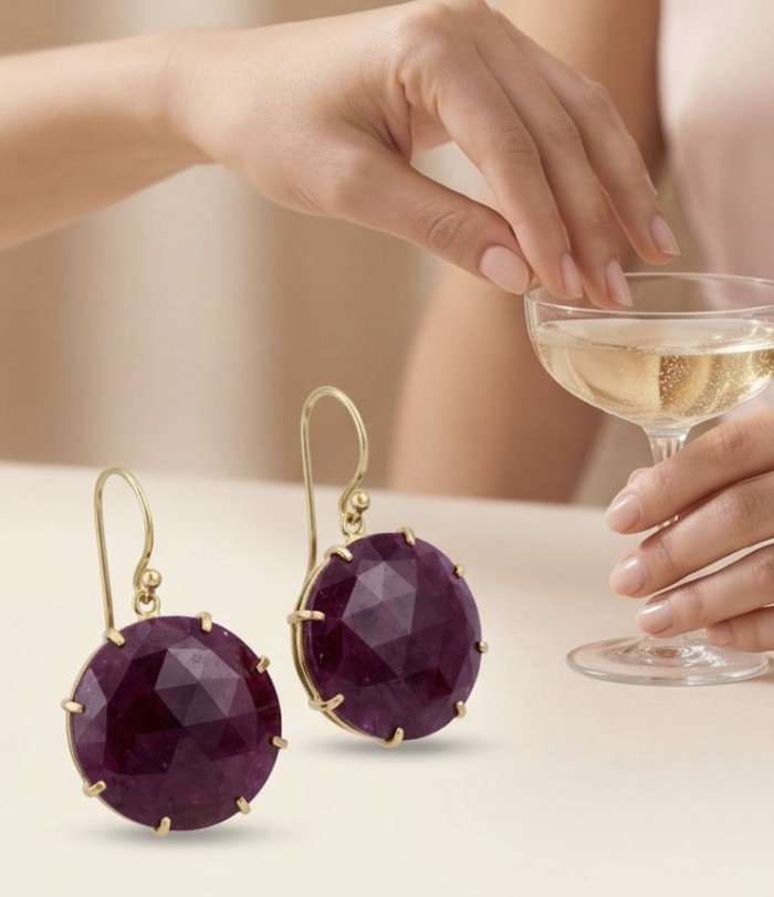 Giovanna Natural 12.4 carat Kasmir Ruby 18K Gold over .925 Sterling Silver handcrafted Statement earrings - Close-up of Giovanna Ruby Earrings with a hand holding a glass of champagne.