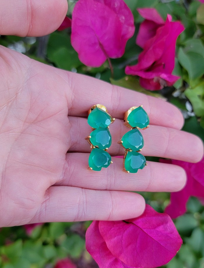 Giovanna - Authentic 21.9 carat Colombian Emerlad .925 Sterling Silver dipped in 22K Gold handcrafted earrings - Close-up of Giovanna emerald earrings in hand against pink flowers.
